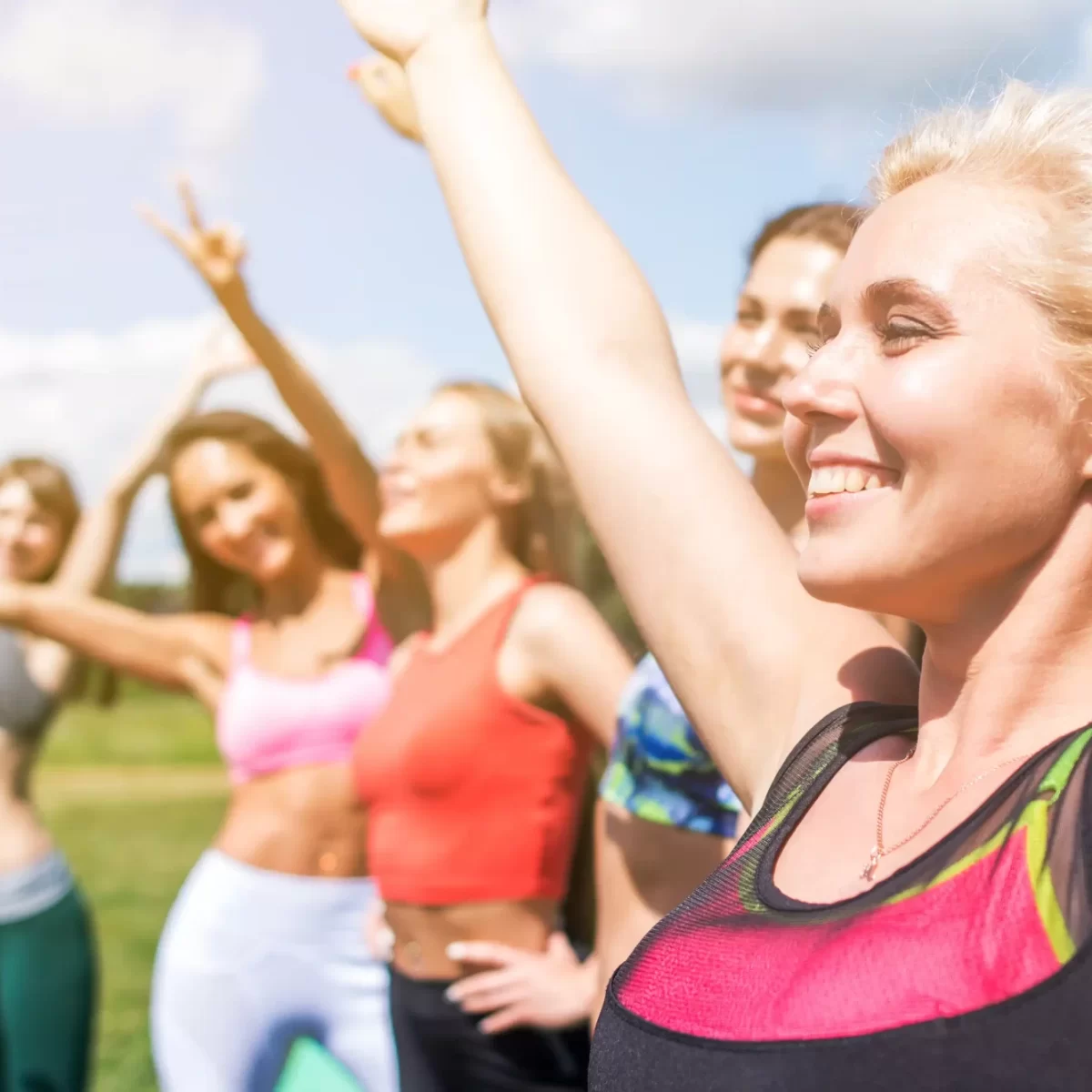 Donne che fanno esercizi all'aperto sorridendo sotto il sole.