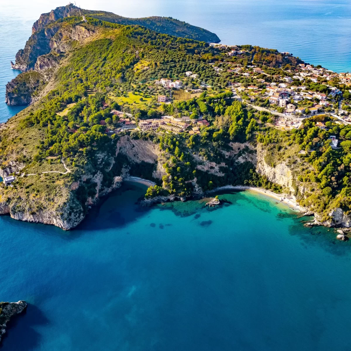 Veduta aerea di una costa panoramica con scogliere, spiagge e vegetazione lussureggiante.