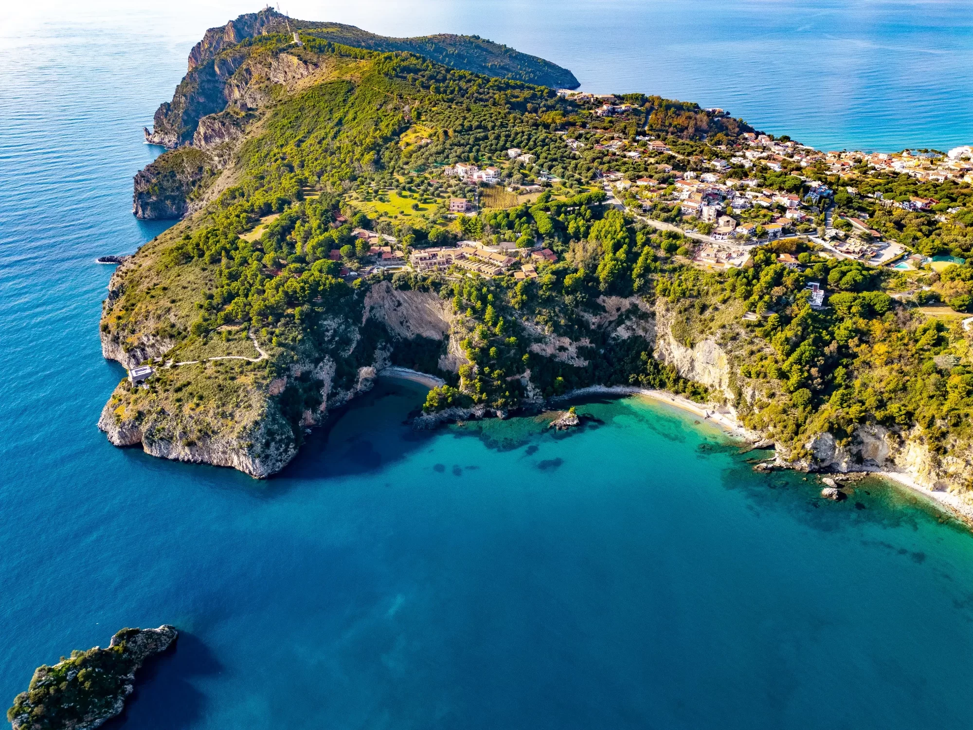 Veduta aerea di una costa panoramica con scogliere, spiagge e vegetazione lussureggiante.