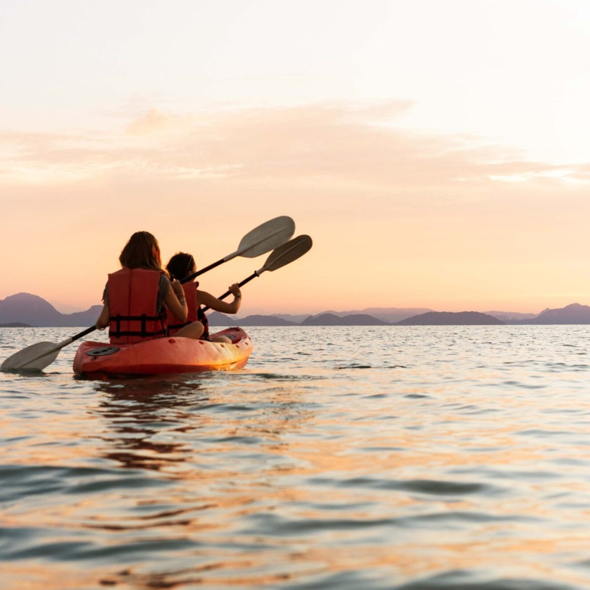 Persone in kayak sul mare al tramonto.