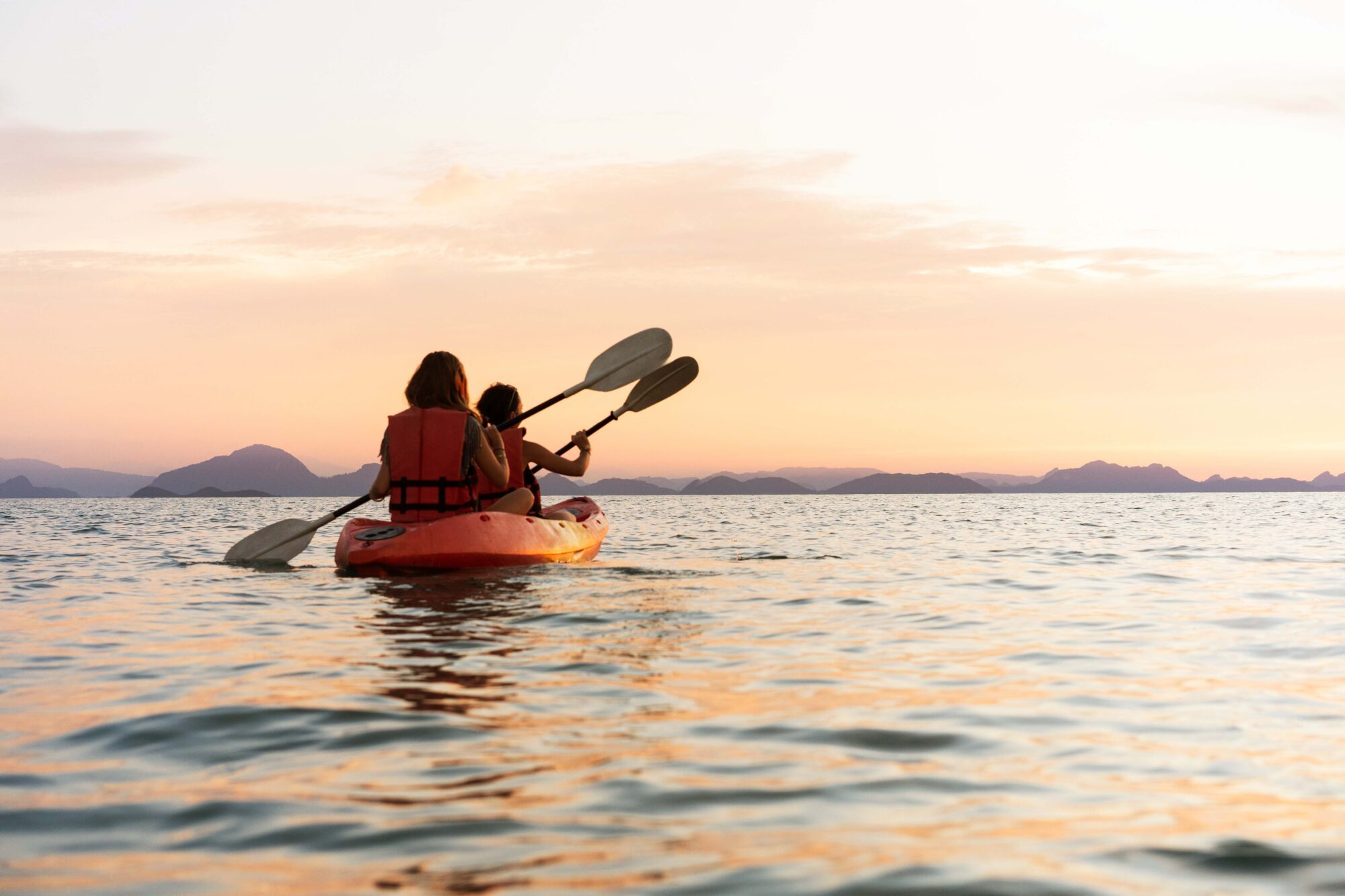 Persone in kayak sul mare al tramonto.