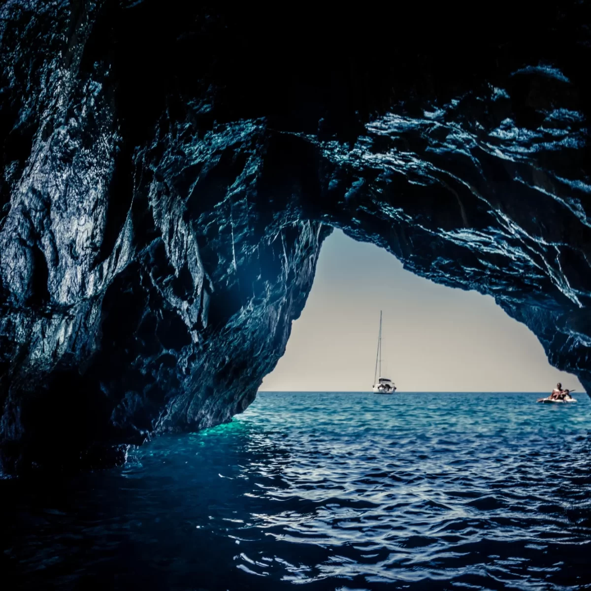 Vista di una barca a vela all'orizzonte da una grotta sul mare.