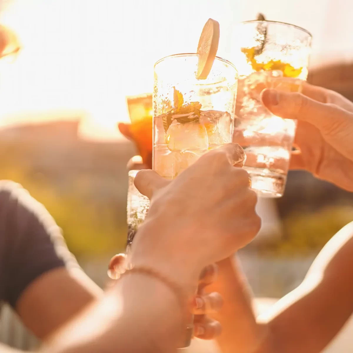 Persone che brindano all'aperto con bicchieri di cocktail al tramonto.