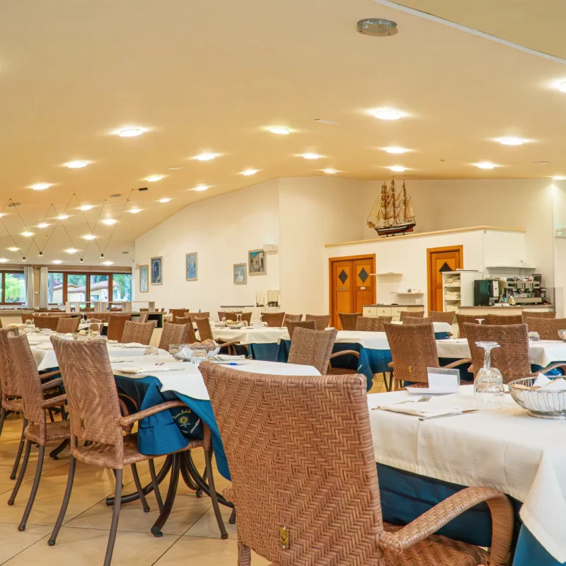 Ristorante elegante con tavoli apparecchiati e sedie in vimini.