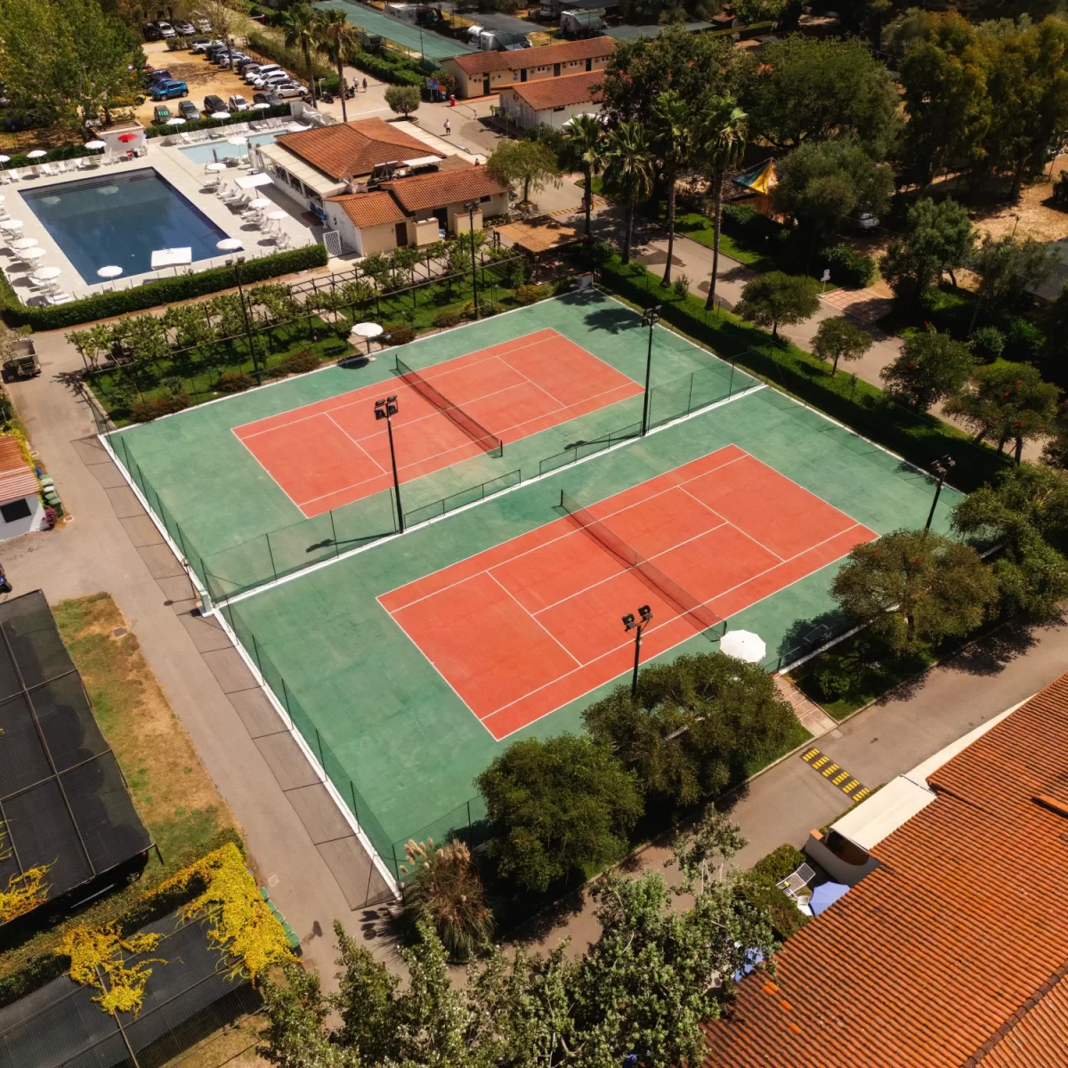 Vista aerea di campi da tennis circondati da alberi e strutture ricreative.